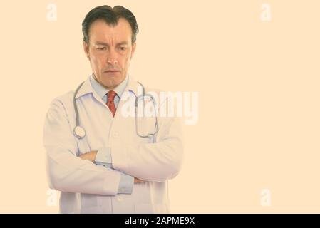 Studio shot of mature bel homme médecin tout en pensant à la recherche vers le bas avec les bras croisés Banque D'Images