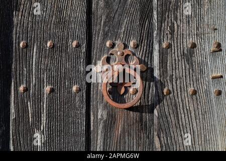 Heurtoir de porte en fer forgé rouillé sur une vieille porte en chêne en bois dans la région des Cotswolds, en Angleterre Banque D'Images