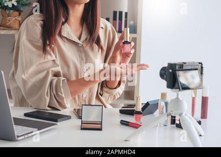 Belle femme asiatique de l'esthétique professionnelle vlog ou blogger présente les produits cosmétiques et l'application de maquillage en caméra frontale pour l'enregistrement vidéo Banque D'Images