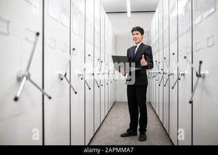 Homme d'affaires, responsable bancaire utilisant un ordinateur portable dans une salle de serveur de casier, coffre-fort avec porte de coffre-fort. Banque D'Images