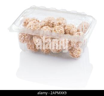 arrondit les bonbons avec des copeaux de noix de coco dans un récipient en plastique isolé sur blanc avec des chemins de découpe Banque D'Images