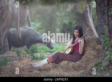 Une femme thaïlandaise jouant à la chanson folklorique avec un instrument de musique traditionnelle PIN (Isan Guitar) Banque D'Images