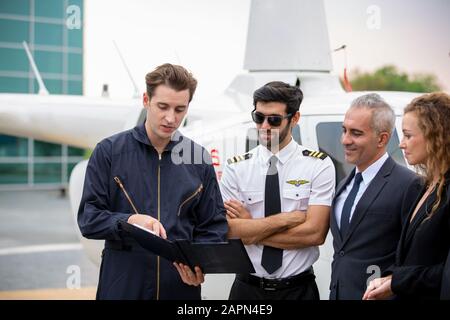 Le technicien signale le contrôle de l'hélicoptère au propriétaire d'une entreprise de service pilote et hélicoptère Banque D'Images