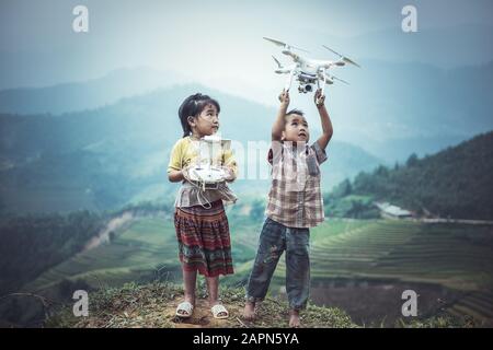 MU CANG CHAI, VIETNAM - SEP 22 , 2016 : enfant exploitant une drone voler ou planant par télécommande dans la campagne du Vietnam Banque D'Images