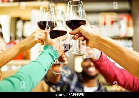 Groupe d'étudiants applaudissant avec du vin rouge au bar à l'apéritif - les jeunes gens joyeux dégustant des boissons au restaurant - bonne humeur et positive avec fr Banque D'Images