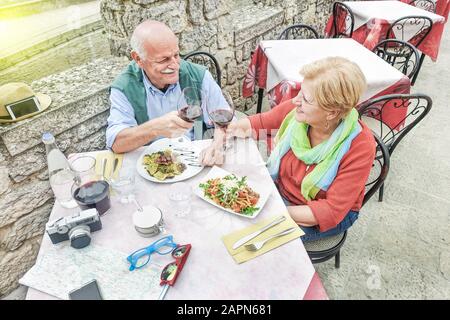 Couple senior qui toaster le vin et manger en plein air - Mari qui a applaudir avec sa femme au restaurant en vacances - Concept De dîner Affectueux - Focus on WO Banque D'Images