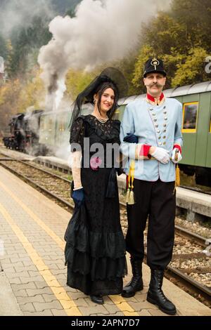 Bled, Slovénie, 4 novembre 2017: Les acteurs jouant à l'Archiduc autrichien Franz Ferdinand et son escorte posent pour une photo devant un train muséal vieux de cent ans qui attend à la gare Bled avant de départir sur la ligne ferroviaire de Bohinj (Transalpina). La ligne a été construite de 1900 à 1906 comme la connexion la plus courte de l'Empire austro-hongrois avec la mer Adriatique à Trieste (Italie). Il a été inauguré en 1906 par l'Archiduc Franz Ferdinand. La reconstitution de l'événement fait maintenant partie d'une visite en train. Banque D'Images