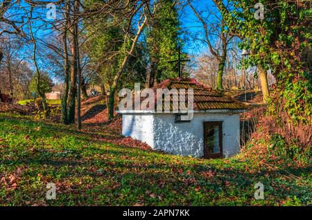 Une petite église pittoresque dans un beau paysage avec des arbres hauts et des feuilles colorées déchus dans une journée ensoleillée.Grèce Banque D'Images