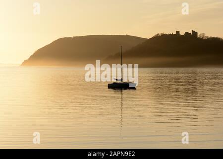 Château de Llansteffan et bateau à voile en début de soirée brouillard coucher de soleil Tywi Estuaire Carmarthenshire Pays de Galles cymru Royaume-Uni Banque D'Images