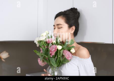 Portrait de la jeune femme asiatique avec fleurs dans la cuisine. Banque D'Images