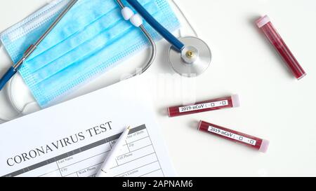 Concept de test sanguin du coronavirus. Bureau de visualisation supérieur à l'hôpital avec formulaire médical de test de coronavirus, tubes à essai avec sang du patient, stéthoscope et respiat Banque D'Images