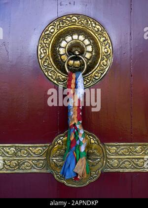 Défonce de porte traditionnelle en laiton magnifiquement décorée avec des rubans colorés sur le temple bouddhiste de Pokhara, au Népal Banque D'Images