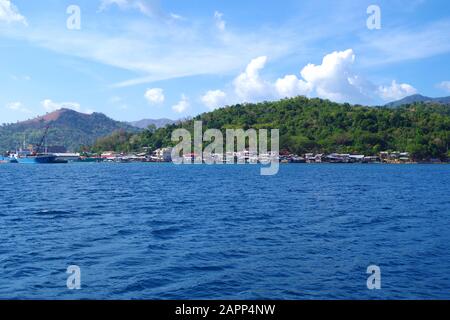 Une petite ville colorée ensergeant la côte d'une île dans l'archipel des Philippines. C'est une belle journée ensoleillée d'été sur un océan bleu et calme. Banque D'Images