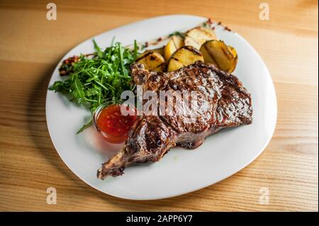 Un steak juteux, délicieux, cuits sur le grill, se trouve avec légumes et sauce sur une assiette blanche. Banque D'Images