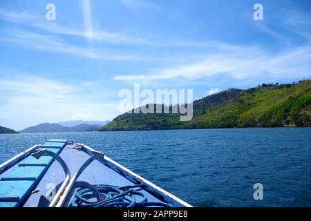 Vue d'un bateau en direction de la grande île boisée de l'archipel des Philippines. L'île est entourée par les eaux bleues et calmes de l'océan. Banque D'Images