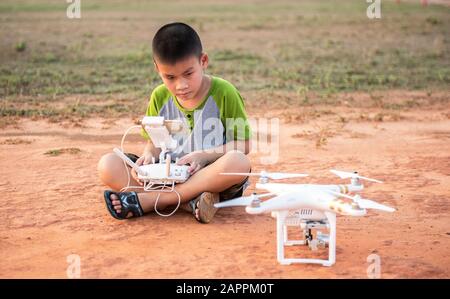 Portrait d'un enfant avec un drone quadricoptère à l'extérieur. Joyeux garçon jouant avec un drone volant avec un appareil photo contrôlé par smartphone Banque D'Images