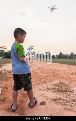 Portrait d'un enfant avec un drone quadricoptère à l'extérieur. Joyeux garçon jouant avec un drone volant avec un appareil photo contrôlé par smartphone Banque D'Images