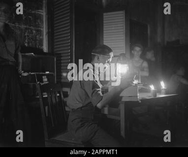 [Un soldat ouvre un paquet aux chandelles et à la lumière d'une lampe à huile] Date: 1947/01/01 lieu: Indonésie, Antilles néerlandaises de l'est Banque D'Images