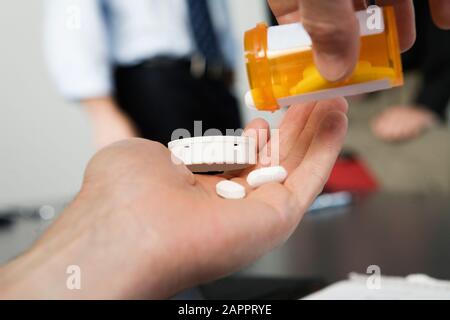 Vue d'un homme d'affaires qui prennent des médicaments dans le bureau. Banque D'Images