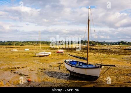 Voiliers à marée basse sur la côte de l'Ile-Grande dans le nord de la Bretagne, France, sous un ciel bleu nuageux. Banque D'Images