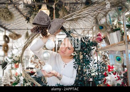 Femme créant un arrangement de décoration de Noël en magasin Banque D'Images