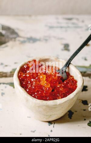 Caviar de saumon rouge dans le bol en céramique avec cuillère sur table en bois ancien. De style rustique, copy space Banque D'Images
