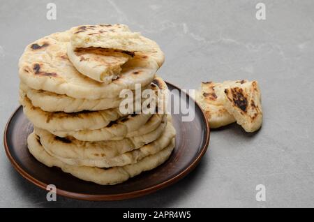 Pain traditionnel Pita maison empilé dans un plat d'argile sur une table de cuisine en pierre Banque D'Images