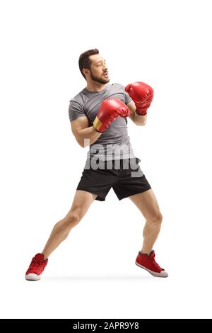 Tir sur toute la longueur d'un jeune homme avec des gants de boxe debout dans une position de garde isolée sur fond blanc Banque D'Images