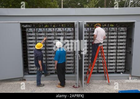 Ouvriers travaillant sur des composants électriques à l'extérieur Banque D'Images