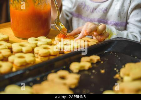 Bébé répandant de la confiture d'orange sur des biscuits en forme de fleur Banque D'Images