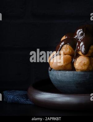 Profiteroles, pâte de choux frais recouverte d'une riche sauce au chocolat Banque D'Images