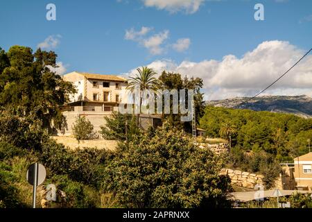 Belle vue d'un bâtiment sur une montagne entourée d'arbres par une journée ensoleillée à Polop, Espagne Banque D'Images