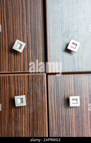 Gros plan vertical d'un placard en bois à quatre portes avec petites poignées carrées Banque D'Images