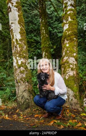 Portrait d'une femme avec son chien dans une forêt tropicale; Langley, Colombie-Britannique, Canada Banque D'Images