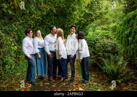 Portrait de famille de parents qui embrassaient et qui regardent les enfants tout en étant debout sur un sentier dans une forêt; Langley, Colombie-Britannique, Canada Banque D'Images