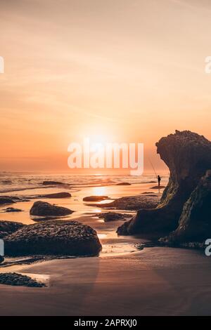 Coucher de soleil à Parangendog Beach avec une personne pêchant de la plage; Purwosari, Yogyakarta, Indonésie Banque D'Images