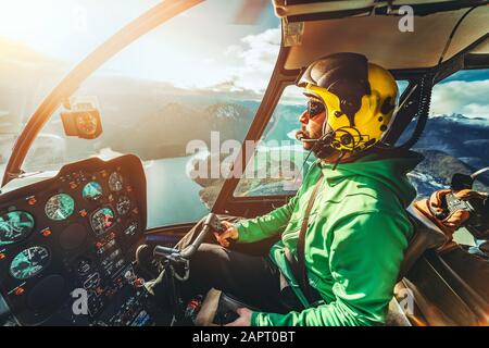 Pilote d'hélicoptère. Hélicoptère volant au-dessus des montagnes et de l'océan. Journée ensoleillée. Vue de l'intérieur de l'hélicoptère. Banque D'Images