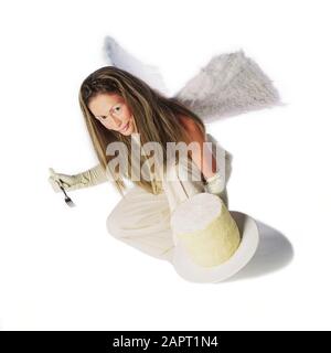 Image studio d'une femme en costume avec les ailes d'ange, tenant une fourchette et un grand gâteau sur une plaque blanche. Banque D'Images