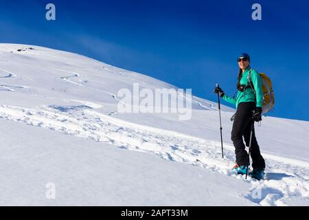 Femme ski de fond, escalade de la montagne dans la peau de piste, sur des skis et des peaux dans Hatcher's Pass, Alaska, Talkeetna Mountains Banque D'Images