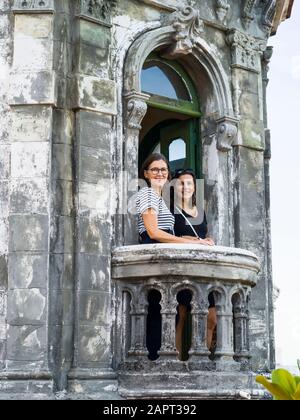 Deux femmes se tiennent sur le balcon d'un ancien bâtiment qui donne sur la caméra, la Havane, Cuba Banque D'Images