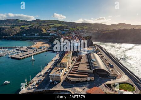 Getaria, Espagne - Mars 11, 2019. Vue sur le village basque de Getaria avec le port de pêche au premier plan et un endroit typique de surf basque. Banque D'Images