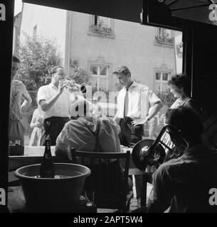 Moselle: Festival du costume et du vin soirée goers et musiciens à l'entrée d'une compagnie de vin Date: 4 juillet 1959 lieu: Allemagne, Kröv, Rhénanie-Palatinat, Allemagne de l'Ouest mots clés: Instruments du vent , musiciens, public, festivals folkloriques, vin, caves à vin Banque D'Images
