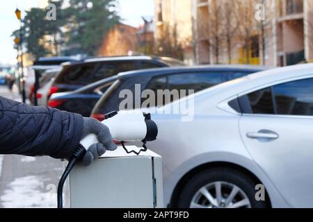 Concept de transport écologique. Station de chargeur électrique de voiture installée dans un complexe résidentiel. La main tient le chargeur pour les voitures électriques. Banque D'Images