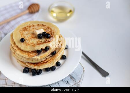 Une pile de délicieuses crêpes aux framboises, aux mûres et aux bleuets. Sur fond clair. Saupoudrés de sucre glace et décorés de min Banque D'Images