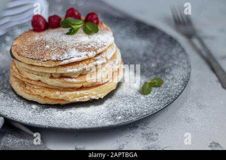 Une pile de délicieuses crêpes aux framboises, aux mûres et aux bleuets. Sur fond clair. Saupoudrés de sucre glace et décorés de min Banque D'Images