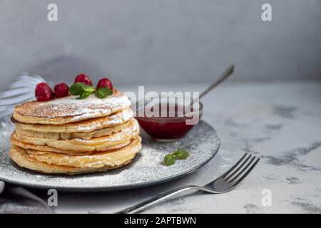 Une pile de délicieuses crêpes aux framboises, aux mûres et aux bleuets. Sur fond clair. Saupoudrés de sucre glace et décorés de min Banque D'Images