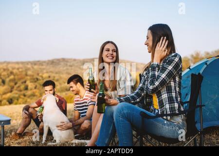 Portrait of cheerful young friends hanging out avec des bières. Groupe d'amis assis à l'extérieur et avoir du plaisir. Banque D'Images