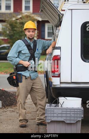 Un ouvrier professionnel récupère les fournitures à partir d'une trappe ouverte sur le côté de son camion de travail Banque D'Images