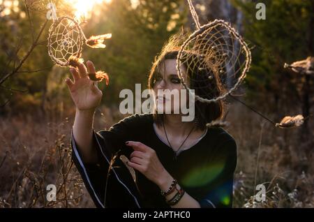 Boho femme avec des cheveux venteux courts. Silhouette féminine avec un capteur de rêve à travers les rayons du soleil Banque D'Images