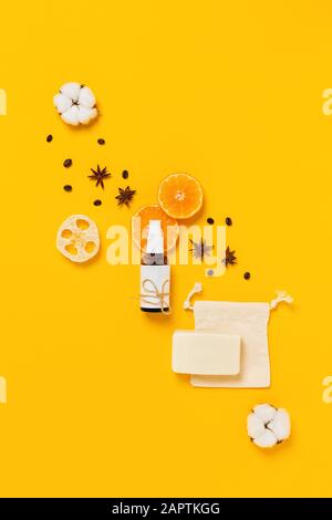 Soins naturels du corps. Bouteille de verre pour parfum, huile ou lotion corporelle entourée de tranches d'orange, cannelle, grains de café, savon naturel et éponge, coton Banque D'Images